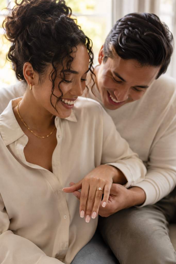 Happy newly engaged couple admiring a moissanite engagement ring together
